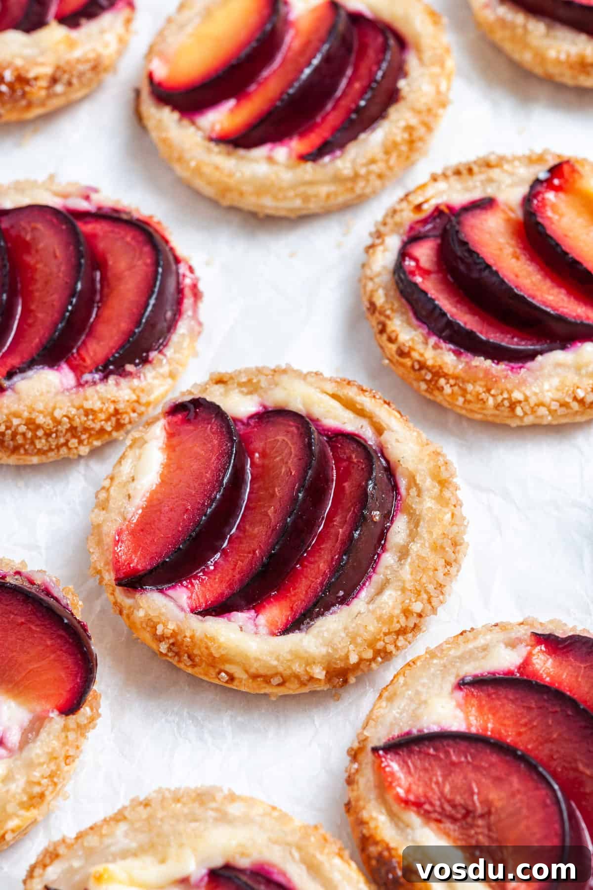 Mini Plum Tarts Recipe: Bite-Sized Homemade Fruit Pastries 6 up close shot of tarts on baking paper.