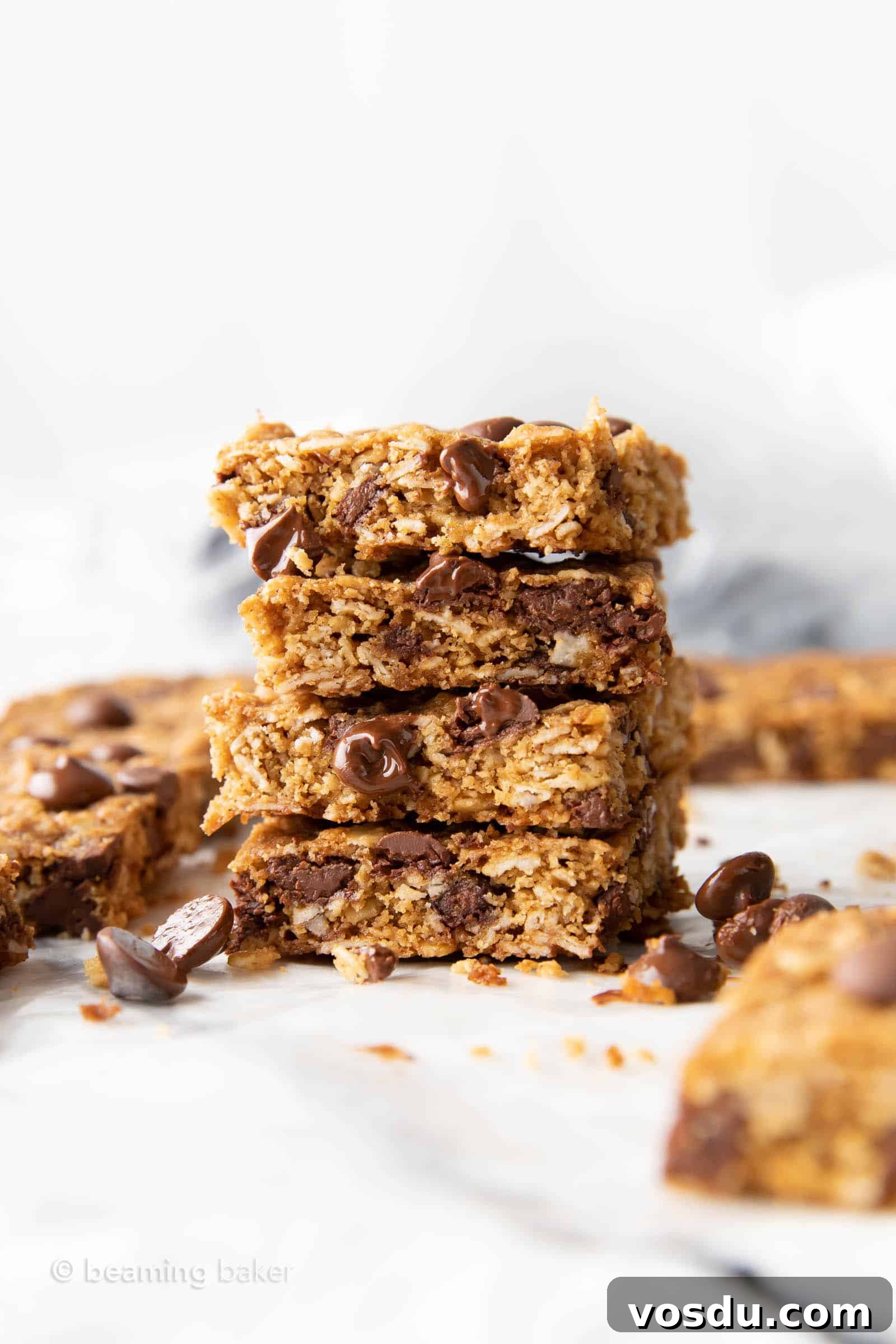 Oatmeal Chocolate Chip Cookie Bars with Wholesome Ingredients 5 a tall stack of healthy oatmeal cookie bars with melted chocolate chips oozing out and sitting nearby on parchment paper