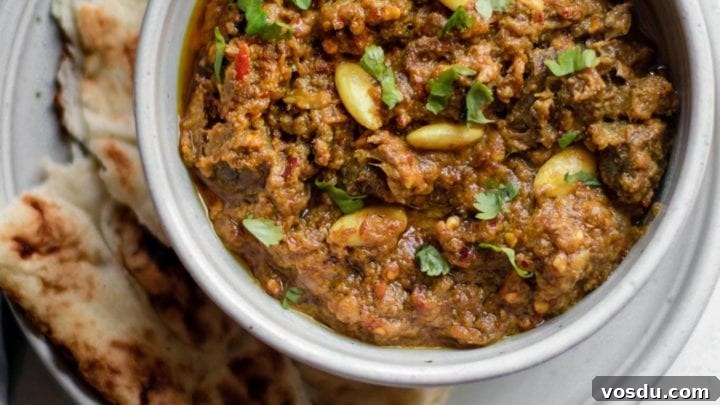 Pakistani Beef Curry (Stew) in a bowl on top of a plate with naan