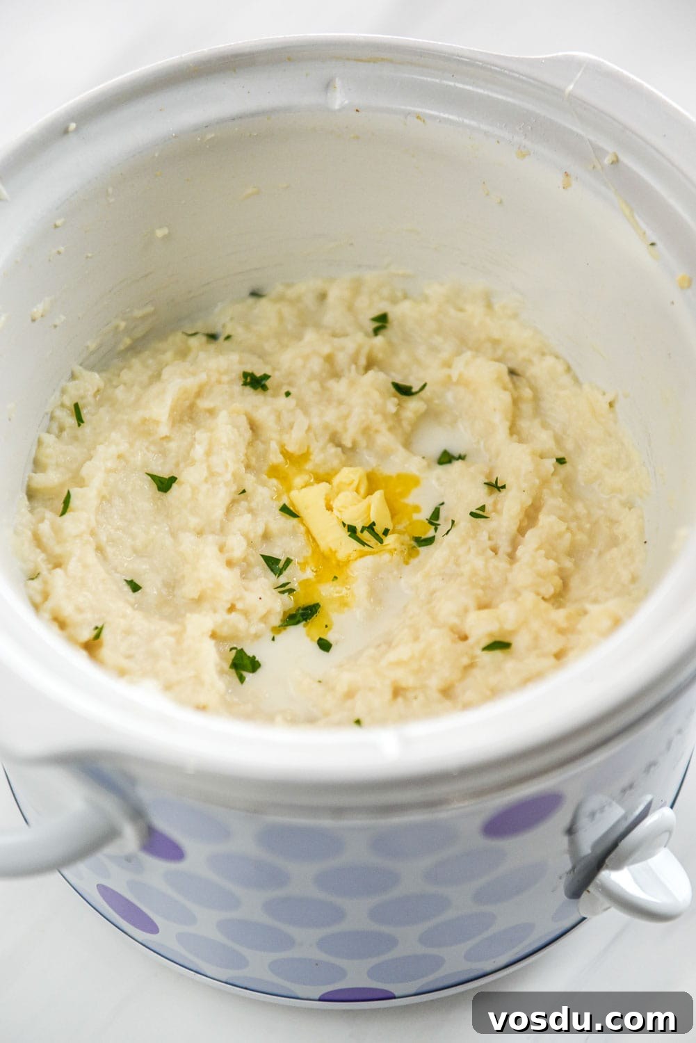 Slow-Cooker Whipped Cauliflower Recipe for Creamy Mash 10 whipped cauliflower with dollop of melted butter in a purple dotted slow cooker