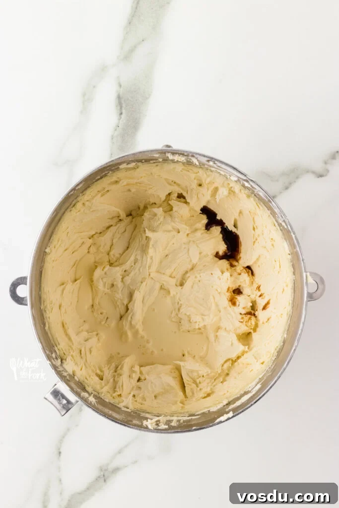 butter and powdered sugar beaten together in a large silver bowl with vanilla extract added, ready to be mixed in