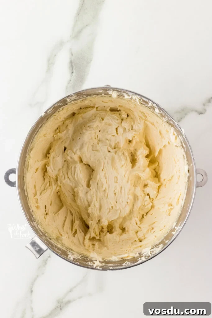 Vanilla buttercream frosting in a large silver bowl ready for Oreo cookie crumbs to be added to make Cookies and Cream frosting