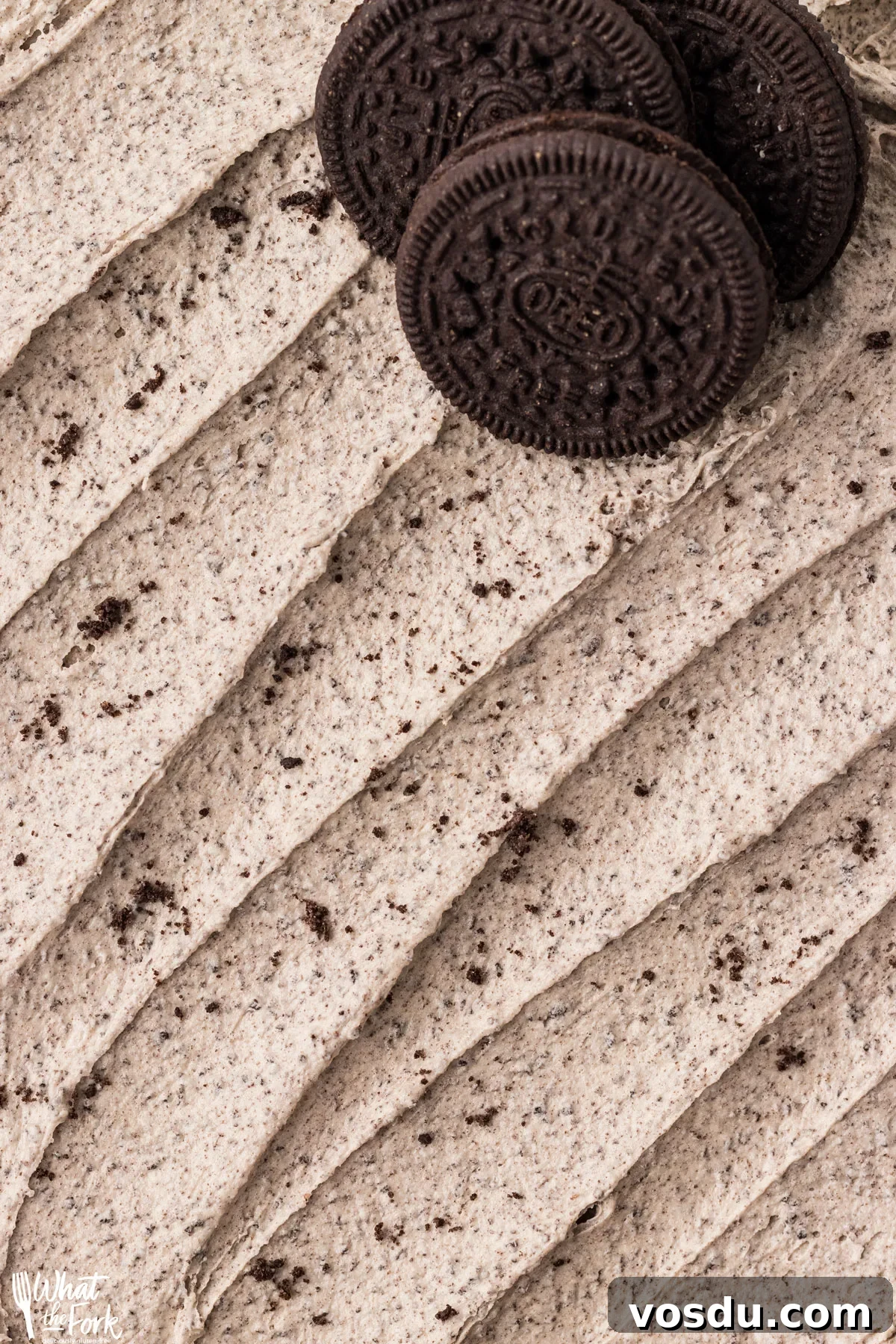 closeup of a Cookies and Cream Frosting Recipe spread on a flat surface with 3 gluten free Oreos in the upper right corner