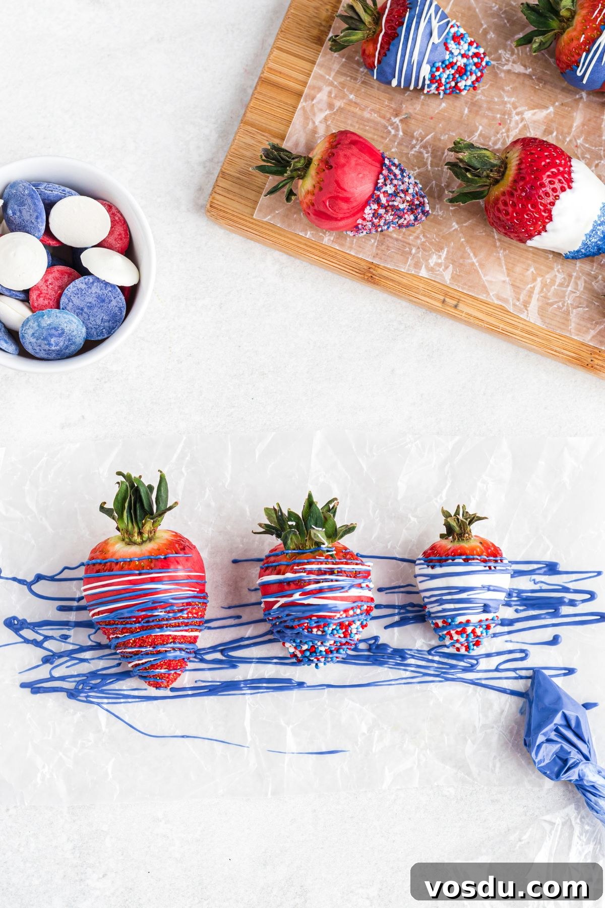 Dipped berries being decorated with drizzles of red, white, and blue candy melts.