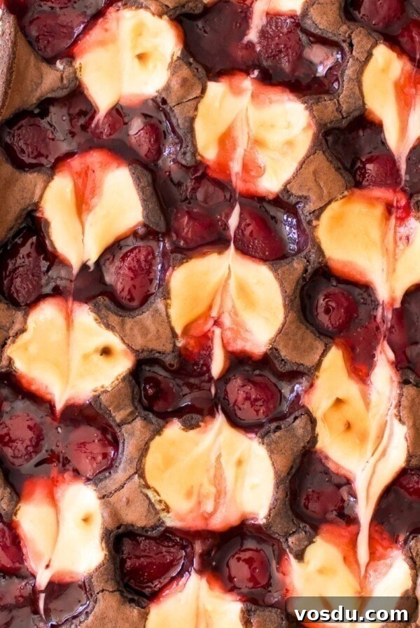 Baked strawberry cheesecake swirled together on top of brownies in a glass dish.