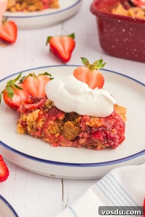 Golden cake crumble on strawberry pie filling on a white plate.