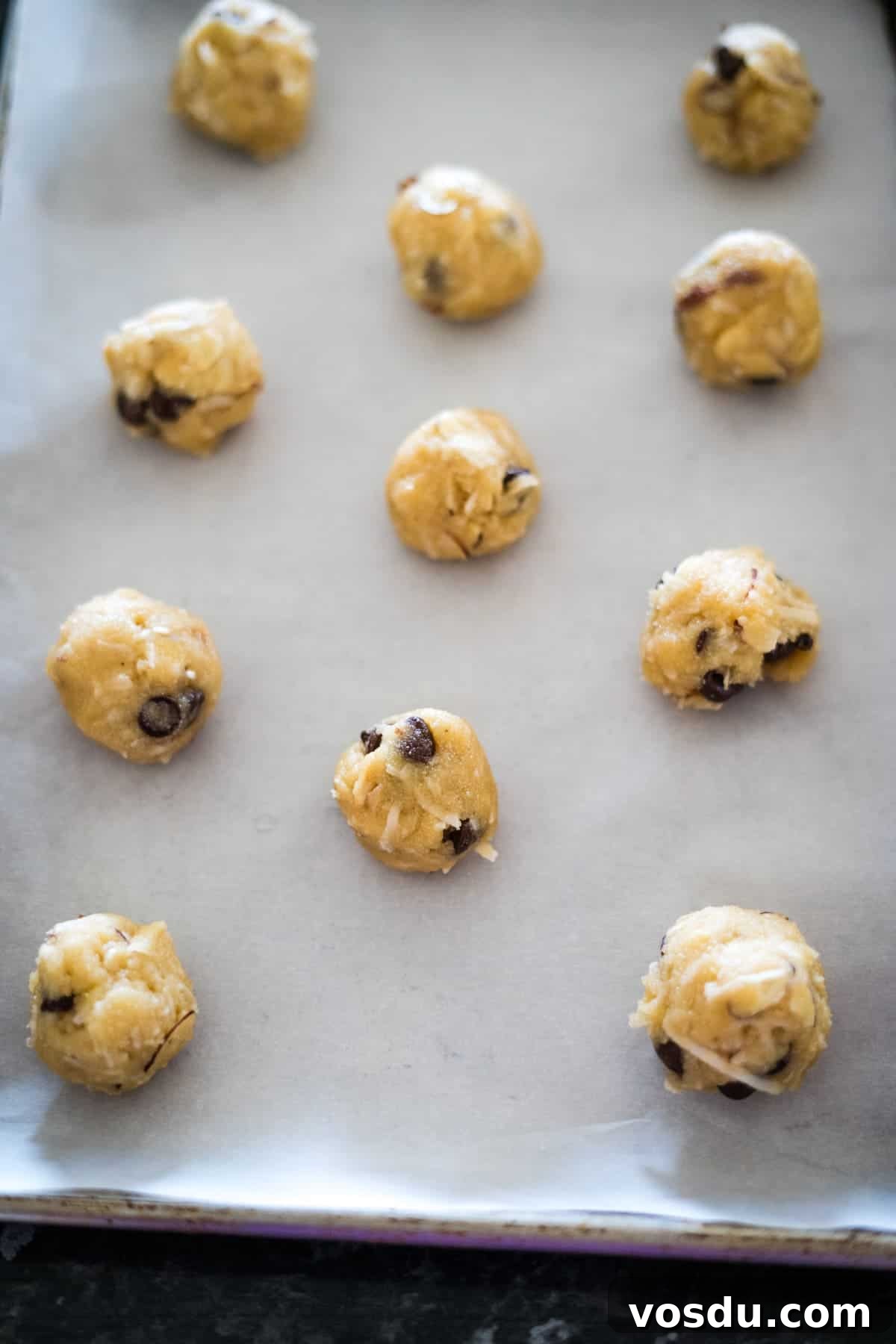 Keto Almond Joy Cookies Recipe — Low-Carb Coconut Chocolate Cookies 8 Twelve cookie dough balls on a parchment-lined baking sheet, ready for baking.