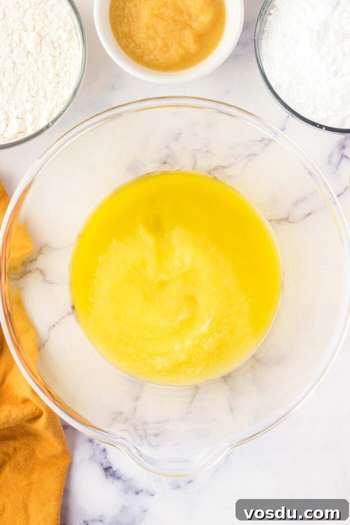 Oil and sugar creamed together in a large glass mixing bowl.