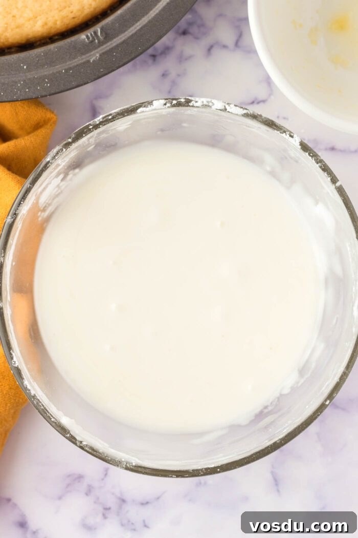 A creamy lemon powdered sugar glaze mixed together in a glass mixing bowl.