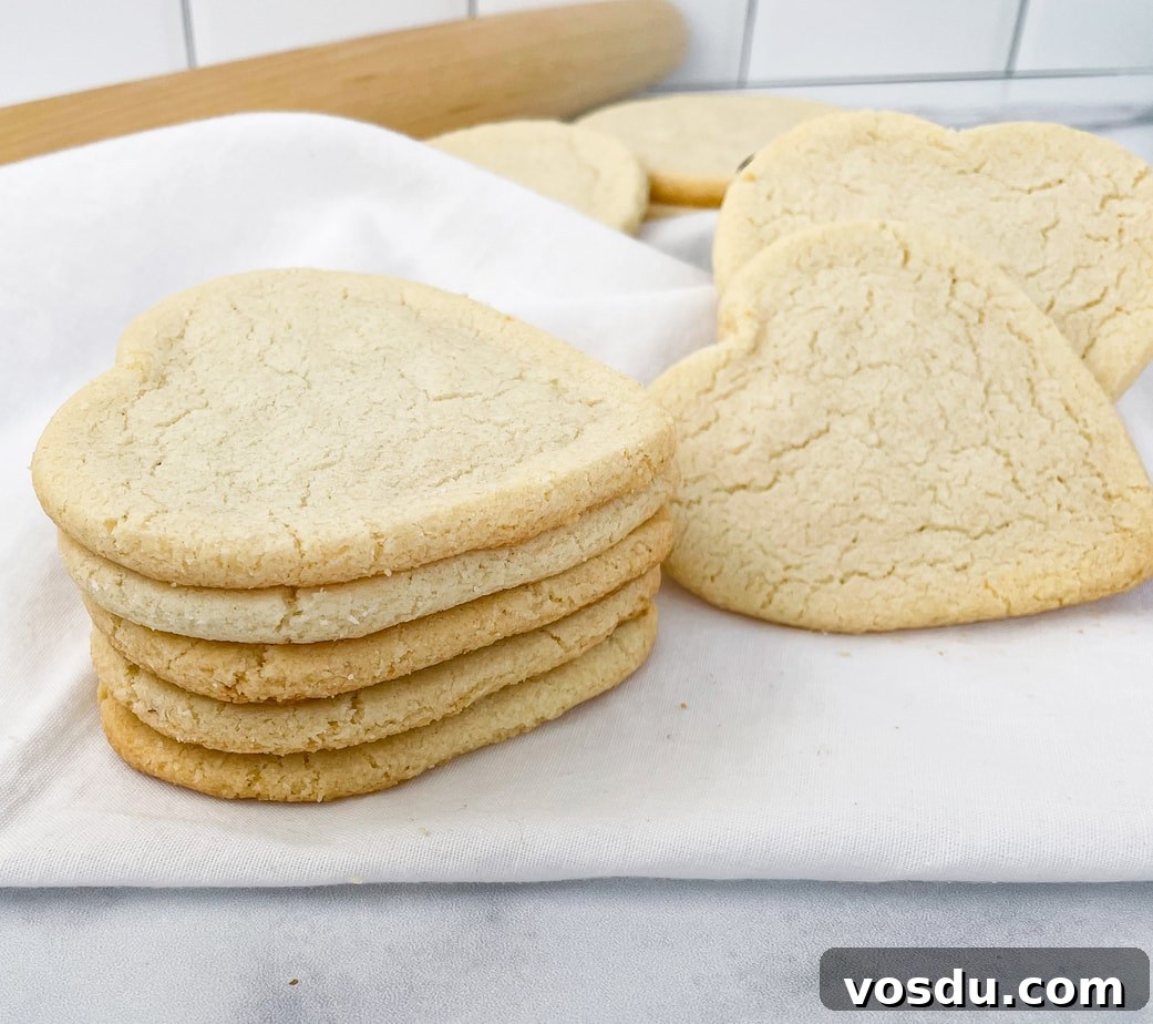 Almond Flour Shortbread Cookies Recipe — Buttery Gluten-Free Treat 4 A stack of heart shaped almond flour cookies on a white napkin. More cookies and rolling pin in the background.