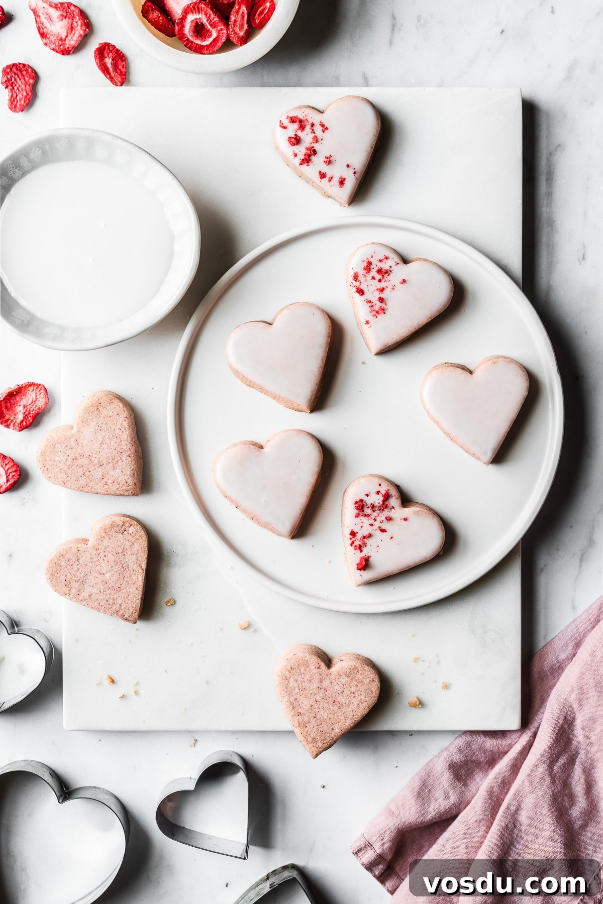 Strawberry Shortbread Cookies Recipe — Simple Homemade Treat 2 Pink heart shaped cookies on a plate and a marble tray
