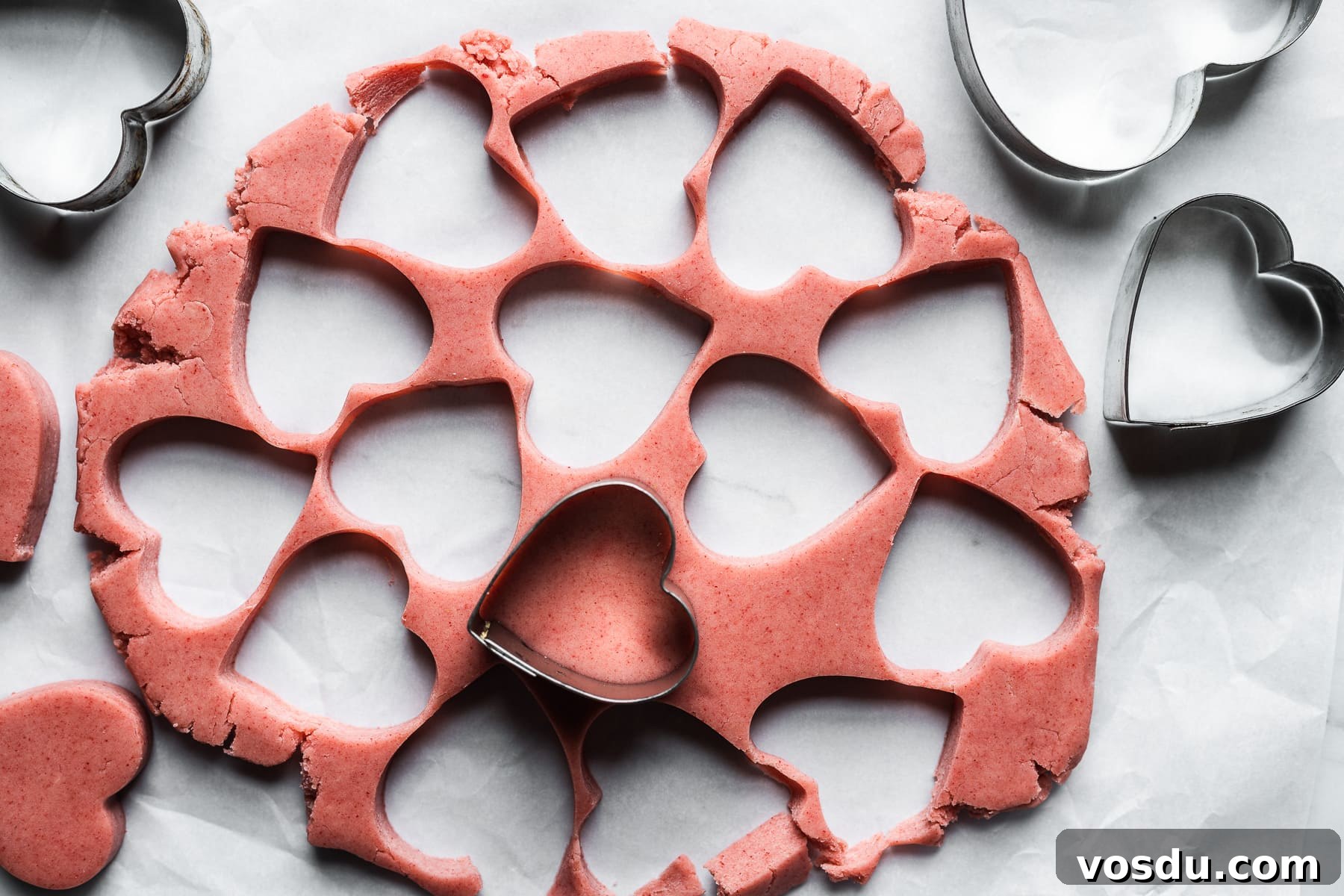 Strawberry Shortbread Cookies Recipe — Simple Homemade Treat 11 Pink cookie dough with heart shaped holes where the dough has been removed.