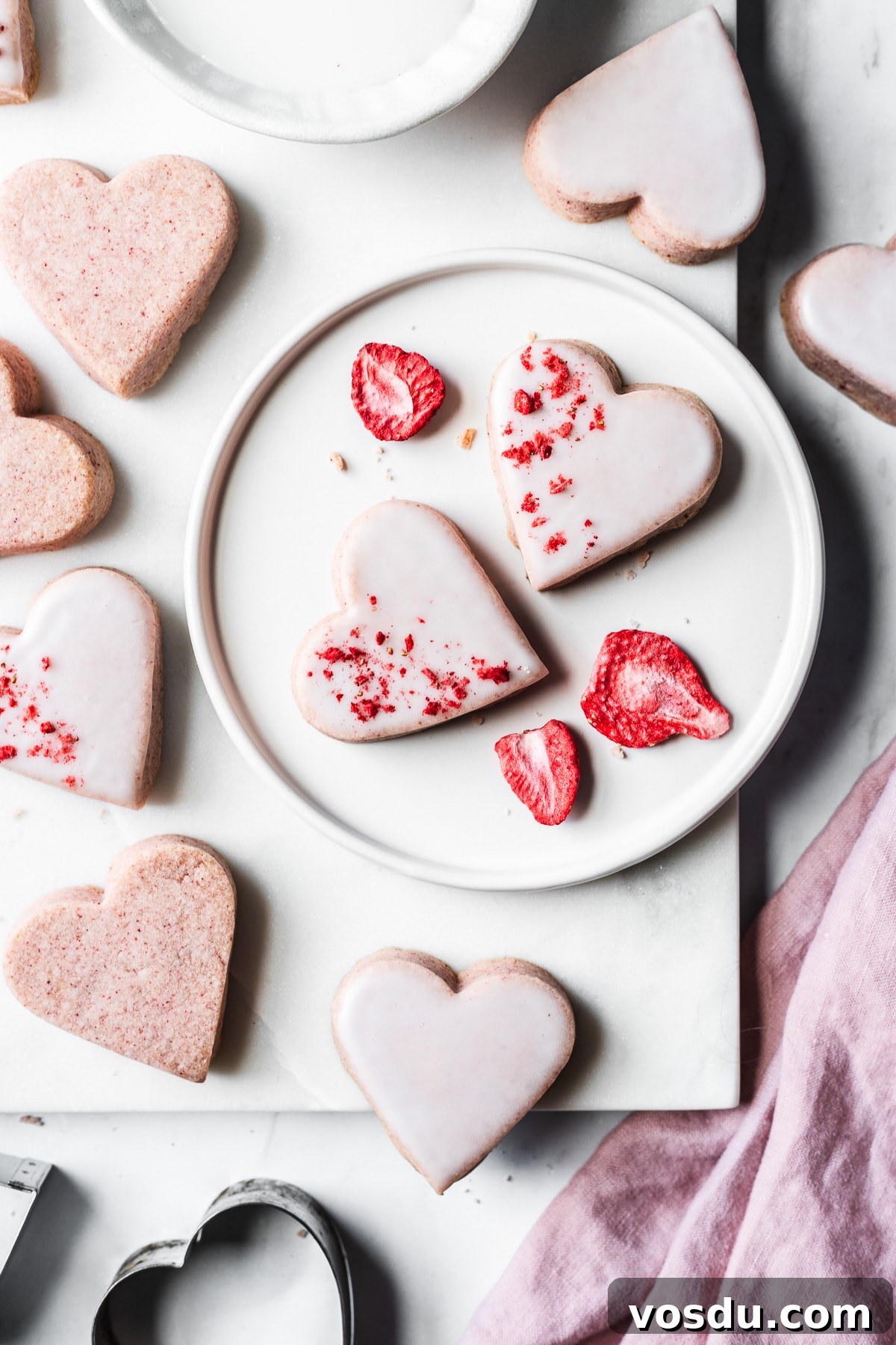 Strawberry Shortbread Cookies Recipe — Simple Homemade Treat 14 Glazed strawberry shortbread cookies on a plate and a marble tray.