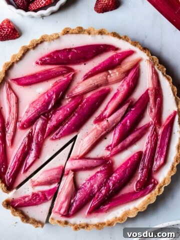 Strawberry rhubarb panna cotta tart with a slice cut into it.
