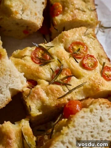 Slices of focaccia topped with cherry tomatoes on white parchment paper.