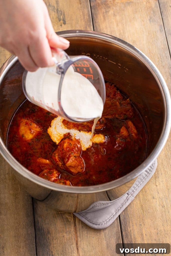 Adding cream in a pot with chicken masala