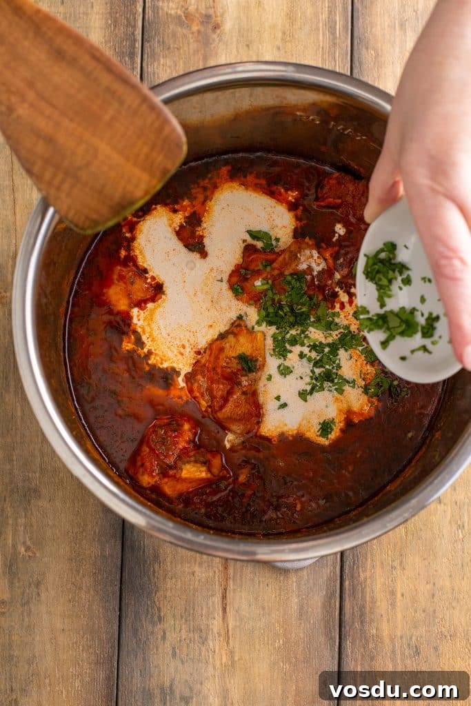 Adding cilantro to chicken masala