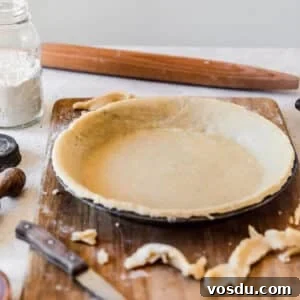 The Ultimate Pie Crust Recipe That Will Wow Your Guests 11 The best pie crust in a metal pan on a wood board with a white background.