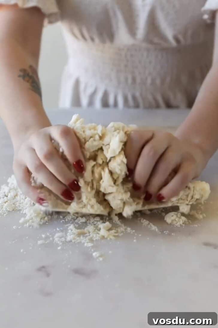 The Ultimate Pie Crust Recipe That Will Wow Your Guests 6 Hands kneading the best pie crust on a marble counter.