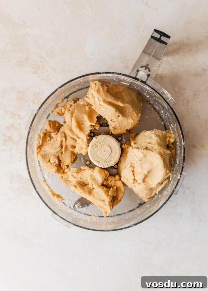 The Ultimate Pie Crust Recipe That Will Wow Your Guests 8 A food processor of the best pie crust on a tan counter.