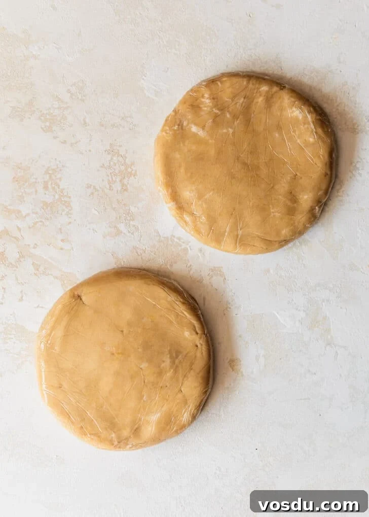 The Ultimate Pie Crust Recipe That Will Wow Your Guests 9 Two discs of the best pie crust on a tan counter.