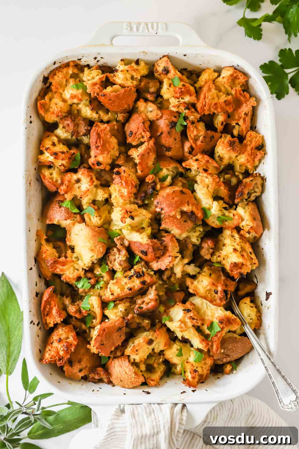 Savory Sausage Stuffing Recipe for Holiday Dinners 2 A baking dish full of sausage stuffing with a serving spoon sticking out.
