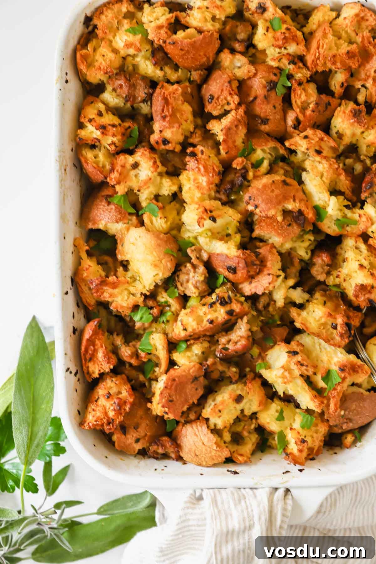 Savory Sausage Stuffing Recipe for Holiday Dinners 8 A baking dish full of sausage stuffing topped with fresh herbs.