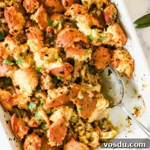 Savory Sausage Stuffing Recipe for Holiday Dinners 10 A baking dish full of sausage stuffing with a portion missing and a serving spoon sticking out.