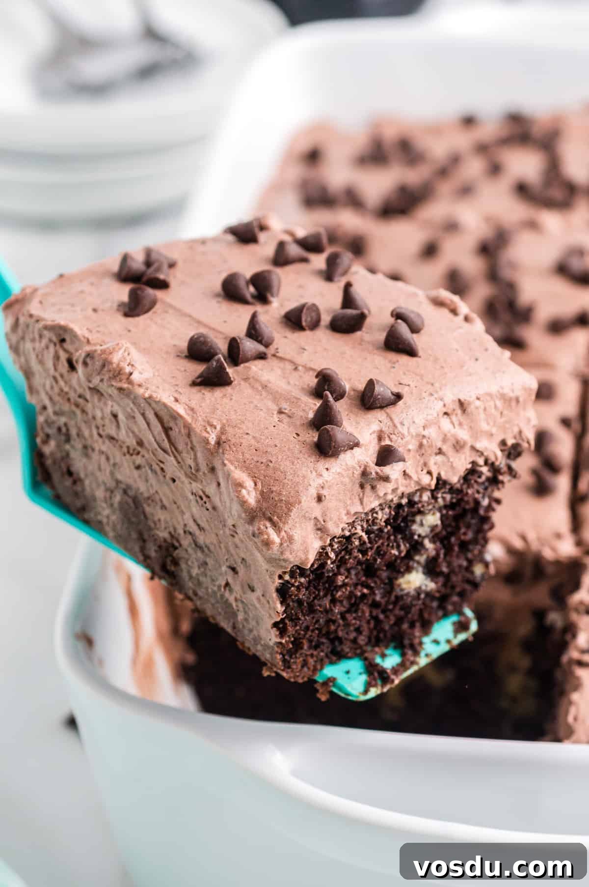 Baileys Irish Cream Poke Cake Recipe for Rich Dessert 12 Server removing a slice of Baileys poke cake from 9 x 13 cake pan
