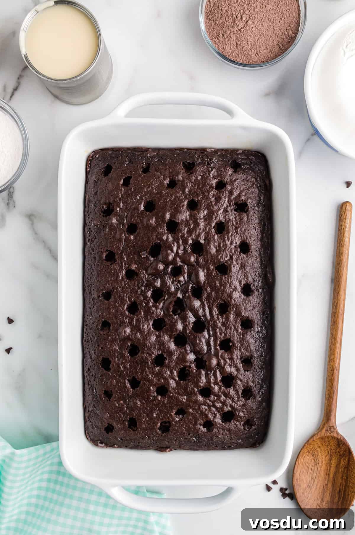 Baileys Irish Cream Poke Cake Recipe for Rich Dessert 7 chocolate cake with holes poked in top with wooden spoon.