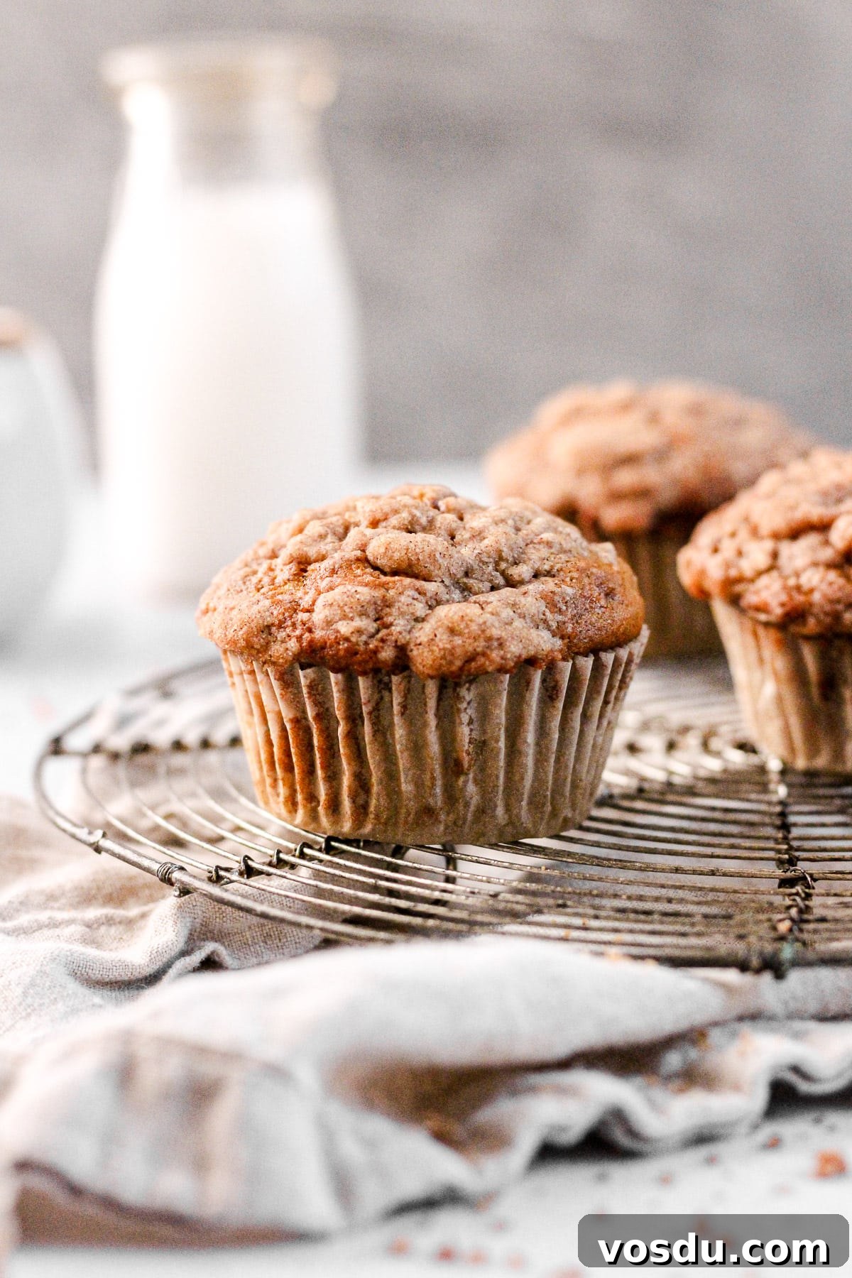 cinnamon banana muffin with streusel topping on a wire cooling rack with a milk jug for baking blog