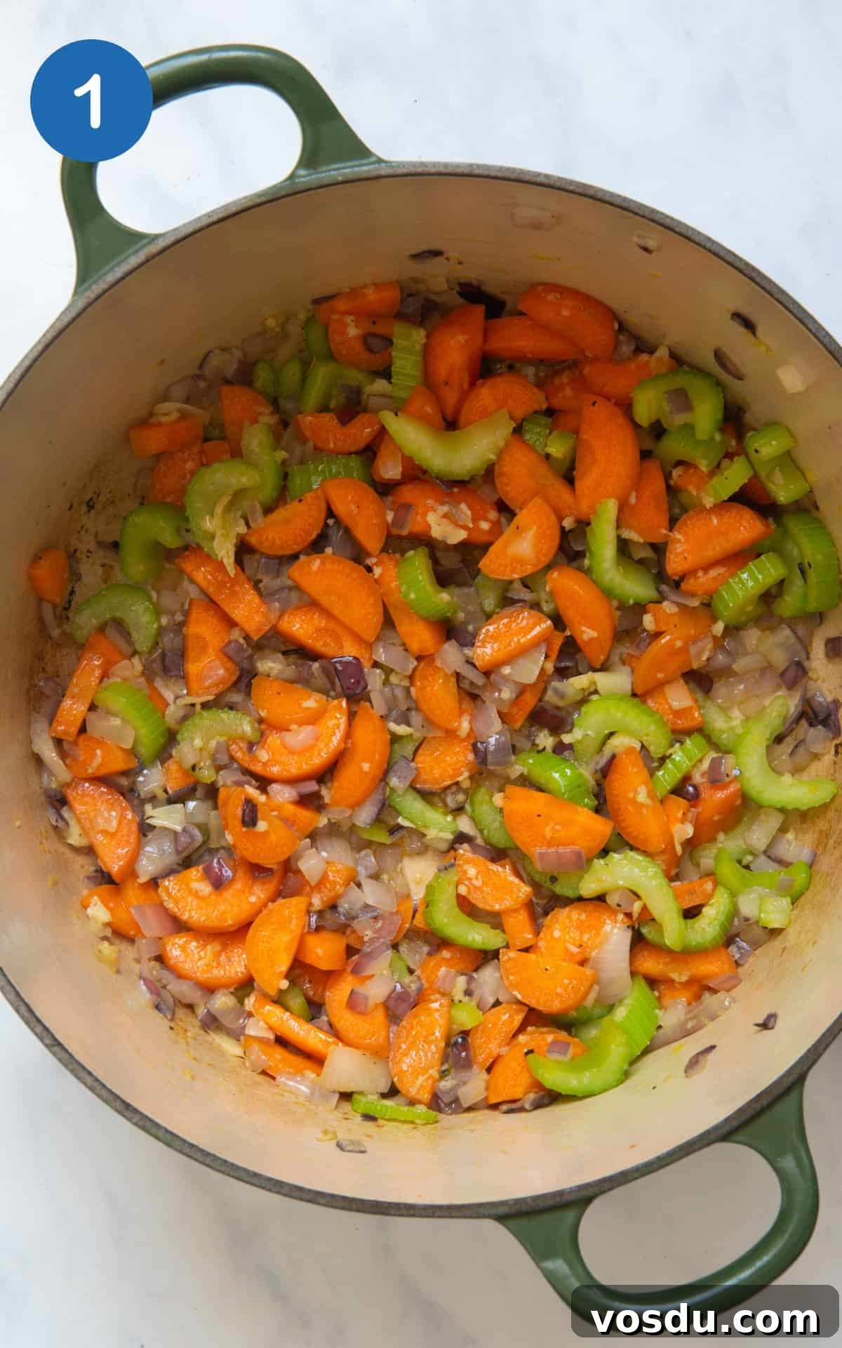 15-Minute Chickpea Stew Recipe for Quick Weeknight Dinners 4 onion, garlic, carrots and celery frying in a large pot. Pot is on a white background.
