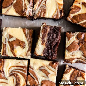 cream cheese swirl brownie on its side next to more brownies.