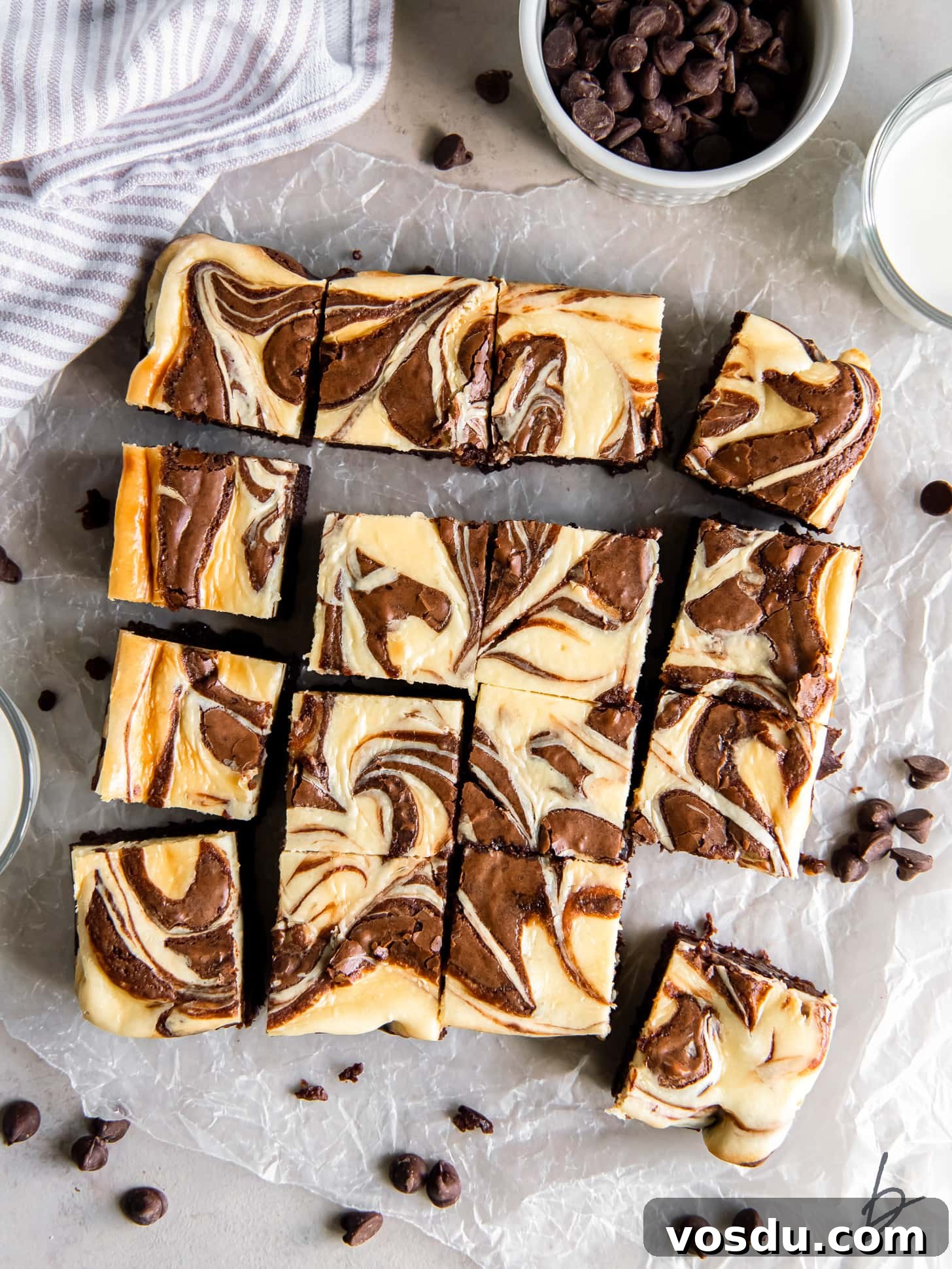 cream cheese swirl brownies cut into squares on parchment paper.