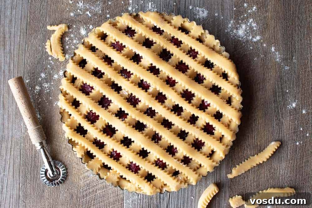 This Strawberry Crostata recipe | Easy Strawberry Tart is an easy Italian pastry filled with fruity jam #strawberrycrostata #crostatarecipe #strawberrytart #crostatadough Top of unbaked strawberry crostata recipe with pastry lattice work.