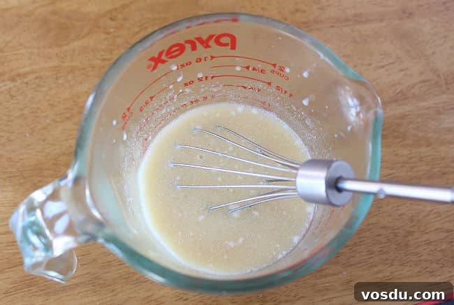 Moist Carrot Muffins with Cinnamon and Maple Glaze 6 Measuring cup with milk and egg being whisked.