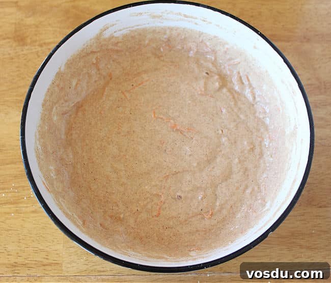 Moist Carrot Muffins with Cinnamon and Maple Glaze 8 Muffin batter in a white bowl on a wood table.