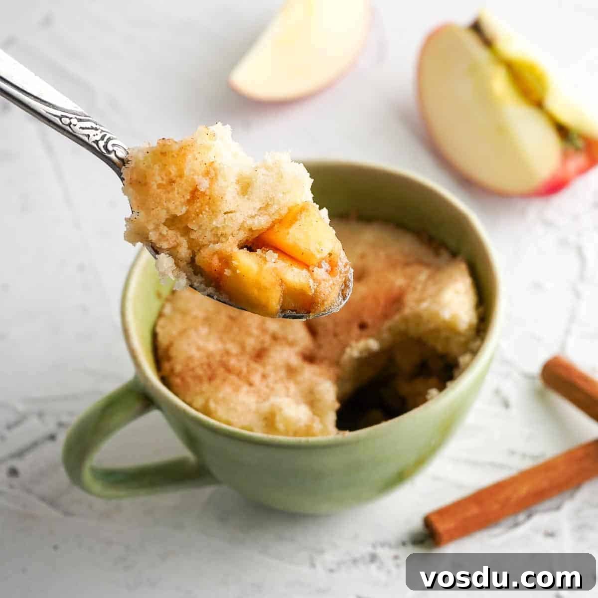 3-Minute Oreo Mug Cake Recipe You Can Make in a Microwave 14 Spoon with apples and cake being held over top cake in a green mug