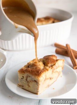 Classic Bûche de Noël Recipe: Traditional French Yule Log Cake 9 bourbon sauce being poured out of small pitcher onto piece of bread pudding on a plate.