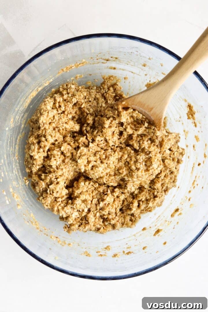 Banana peanut butter oat bar batter mixed in a large glass bowl with a wooden spoon