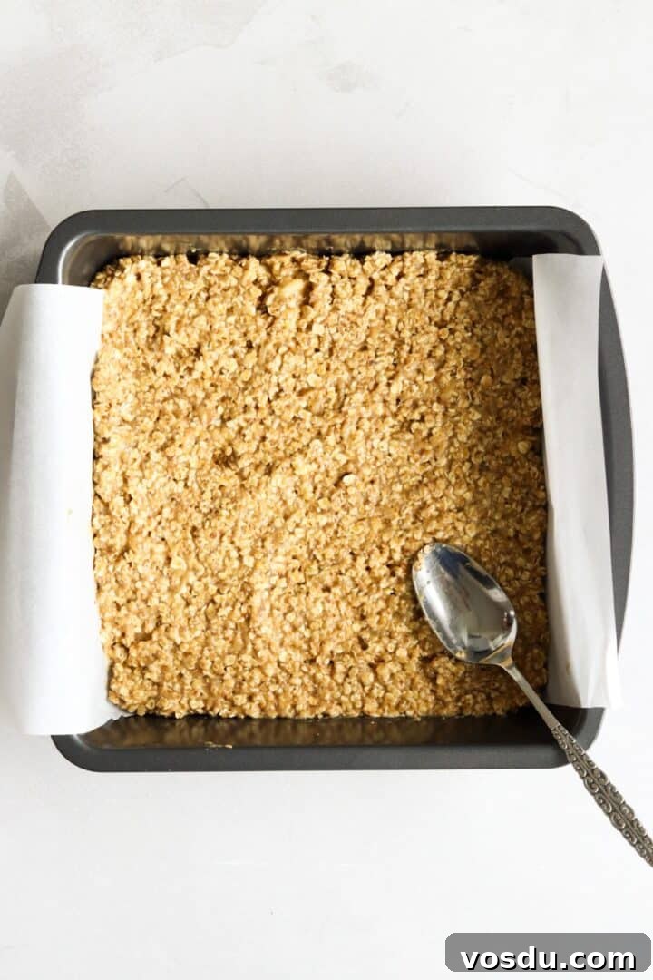 Banana peanut butter oat bar batter spread into a parchment-lined baking pan