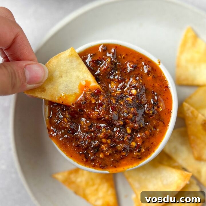 A hand dipping a tortilla chip into a bowl of salsa macha.