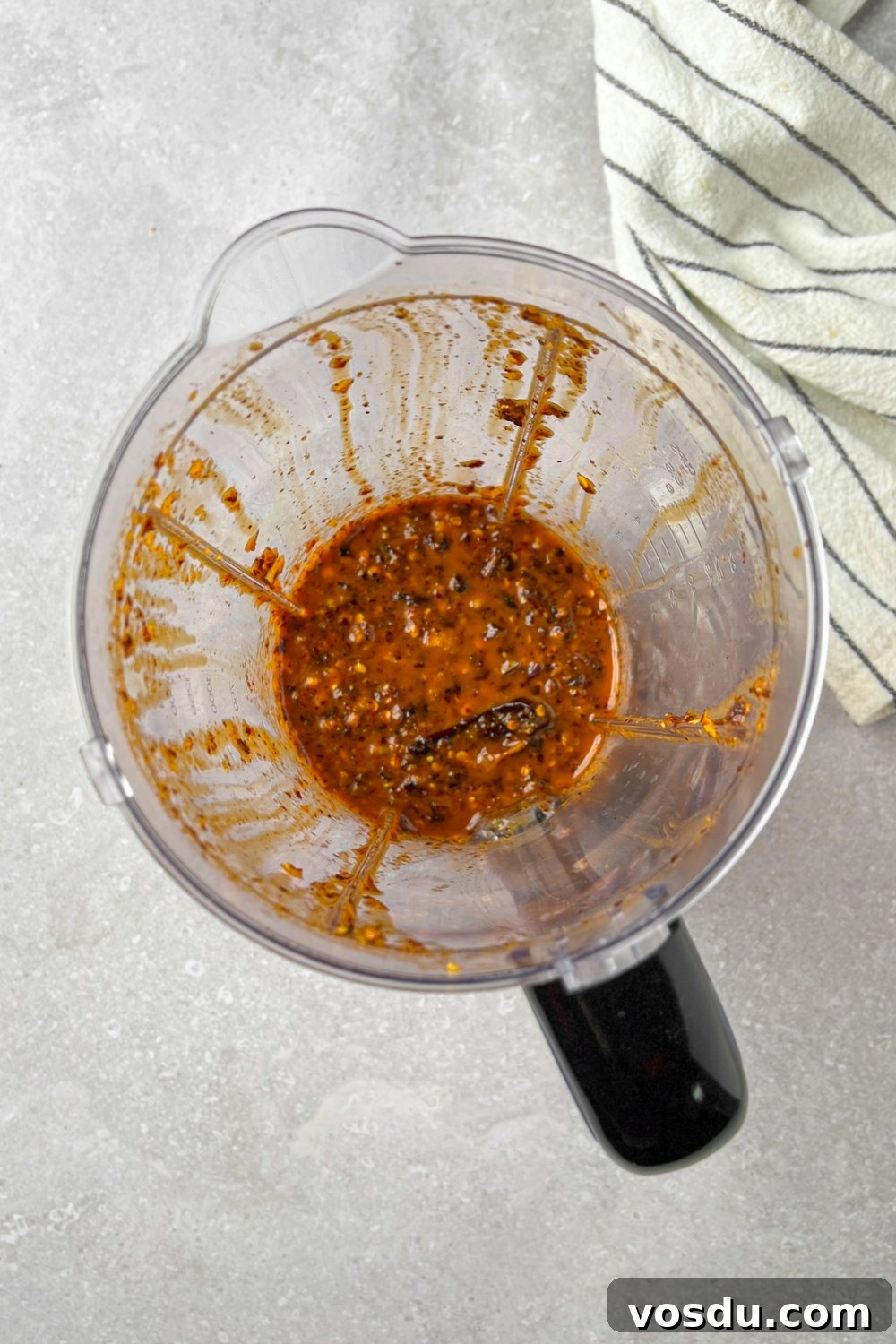 A blender with blended up oil,peppers, and garlic in it.