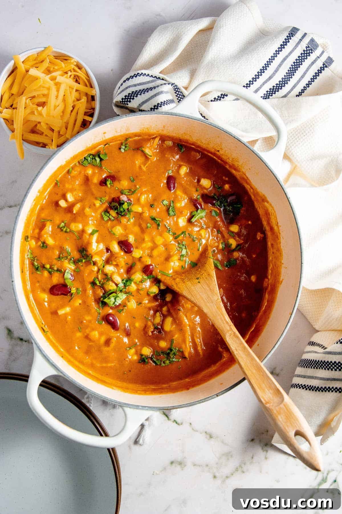 Creamy Chicken Enchilada Soup Recipe for Cozy Weeknight Dinners 2 Soup in a pot with a wooden spoon.
