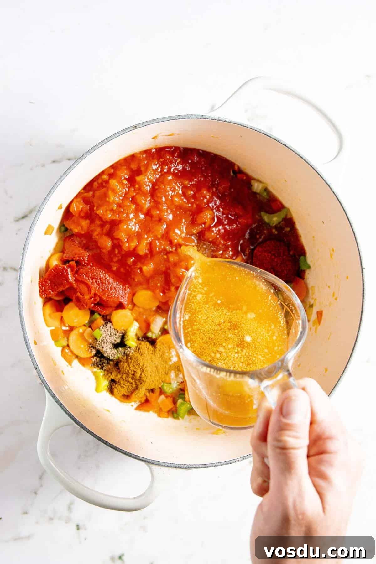 Creamy Chicken Enchilada Soup Recipe for Cozy Weeknight Dinners 5 A person pouring broth into a pot.