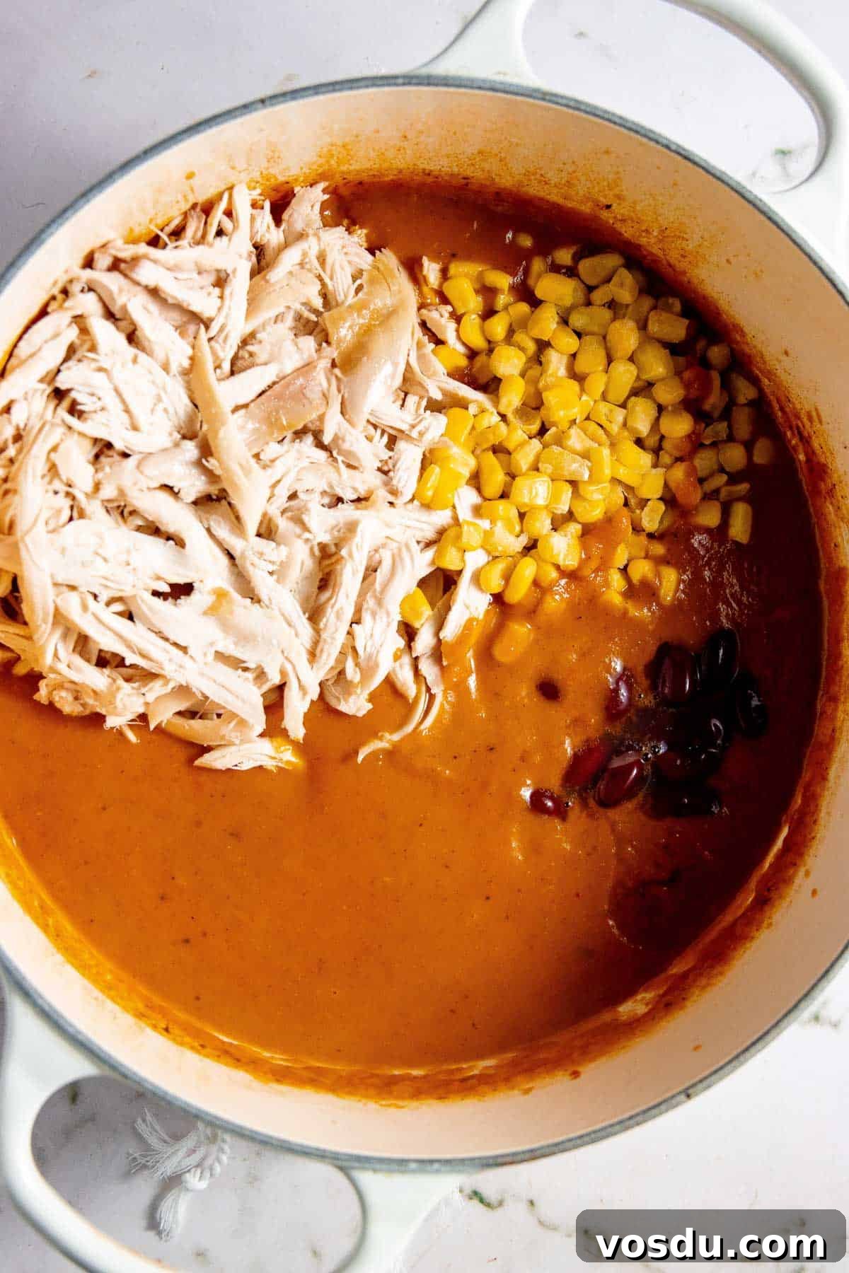 Creamy Chicken Enchilada Soup Recipe for Cozy Weeknight Dinners 7 Enchilada chicken soup in a pot with corn and shredded chicken.
