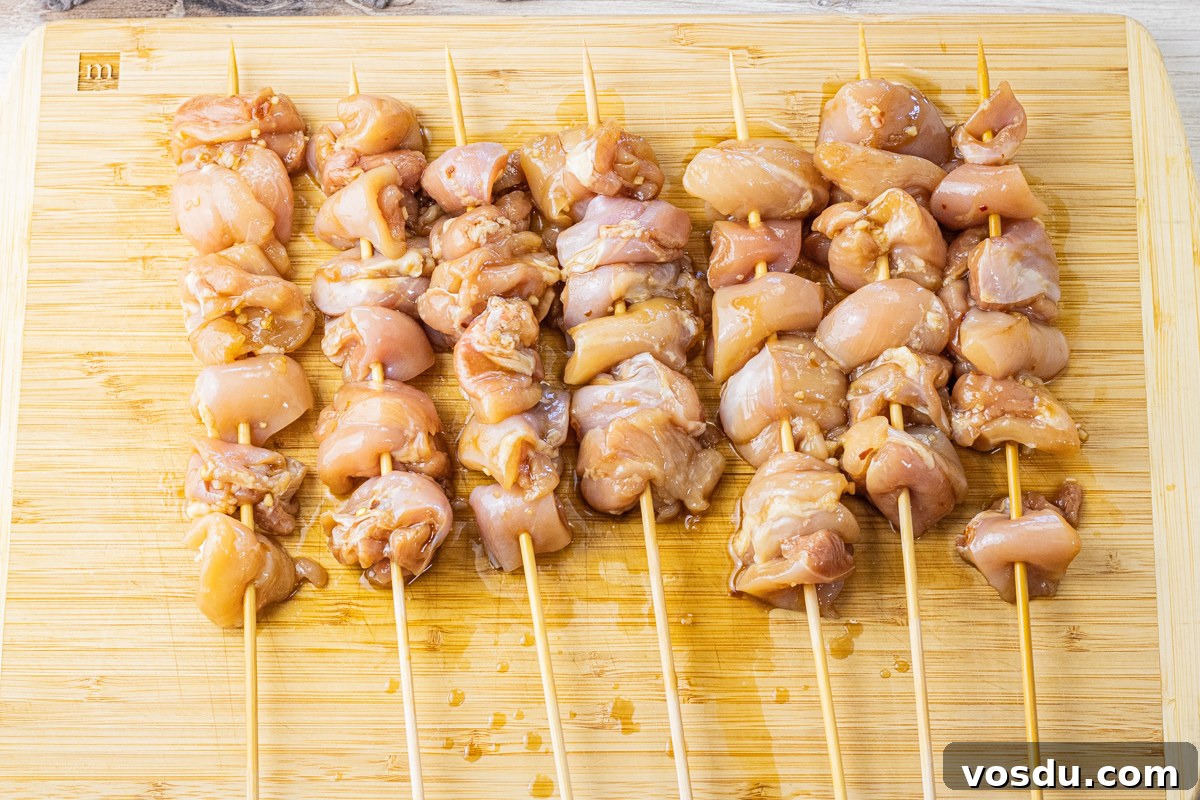 Sticky Teriyaki Chicken Skewers with Sesame and Green Onion 3 raw chicken threaded on wooden skewers on a wooden cutting board