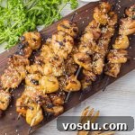 Sticky Teriyaki Chicken Skewers with Sesame and Green Onion 6 grilled chicken skewers on a wooden cutting board