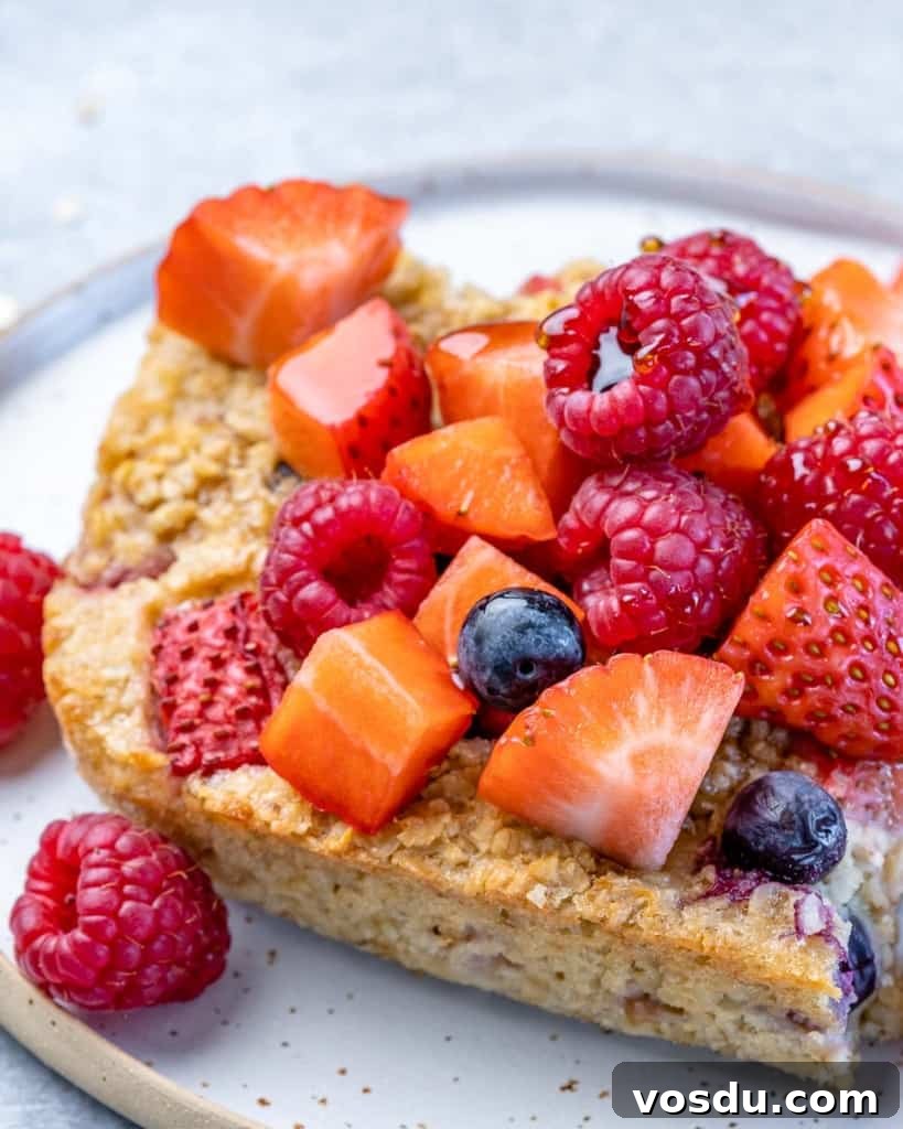 side shot of baked oatmeal slice topped with berries on a plate 