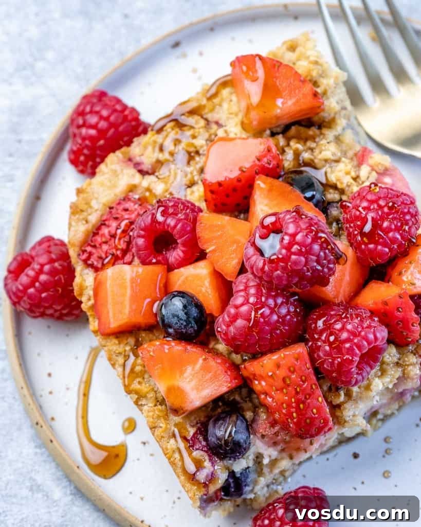 top view of slice of baked oatmeal topped with fresh berries and maple syrup.